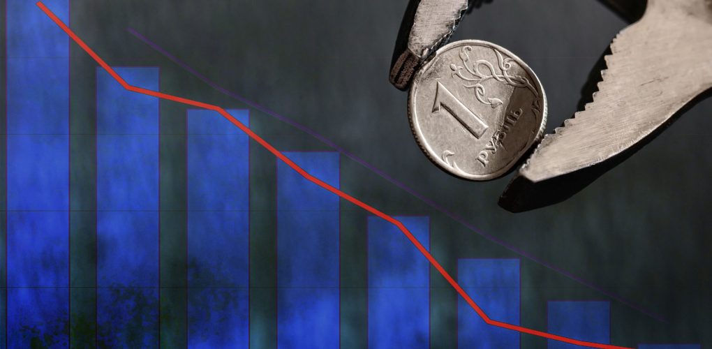 Wrench holds in vise bent metal coin with a face value of 1 Russian ruble. Collapse of the ruble and the economy, sanctions against Russia, the economic crisis in Russia. Copy space, selective focus